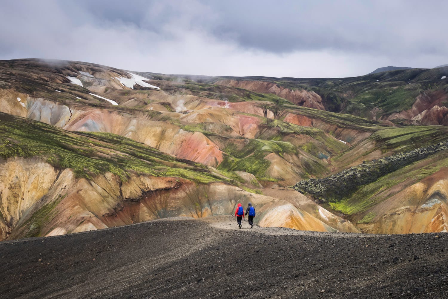 Hikers with backpacks walking on colorful mountains on Laugavegir trail