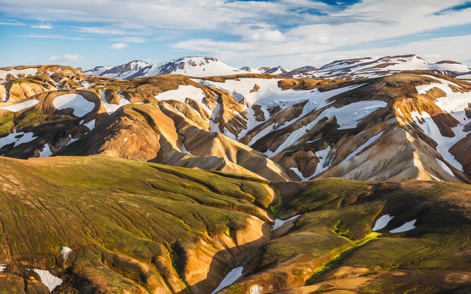 Chocolate colored mountains with snow patches in sunset lights on Laugavegur trail